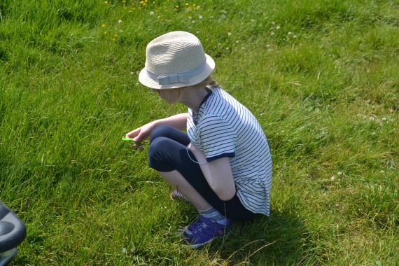 boy crouching looking at grass