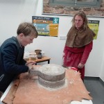 young boy hand milling on old style millstones