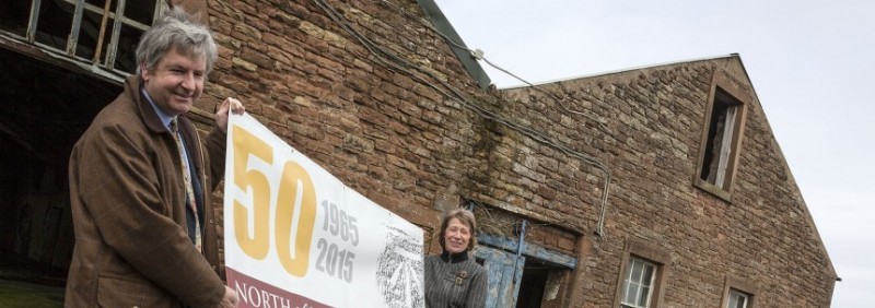 farm buildings with people holding banner