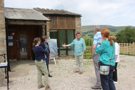 man talking to a group of people outside the mill