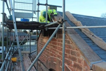 putting the final touches to the barn gable end man working on building